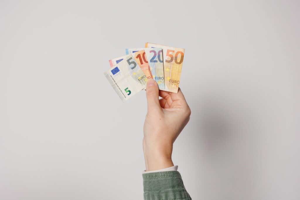 A person's hand holding up multiple currencies